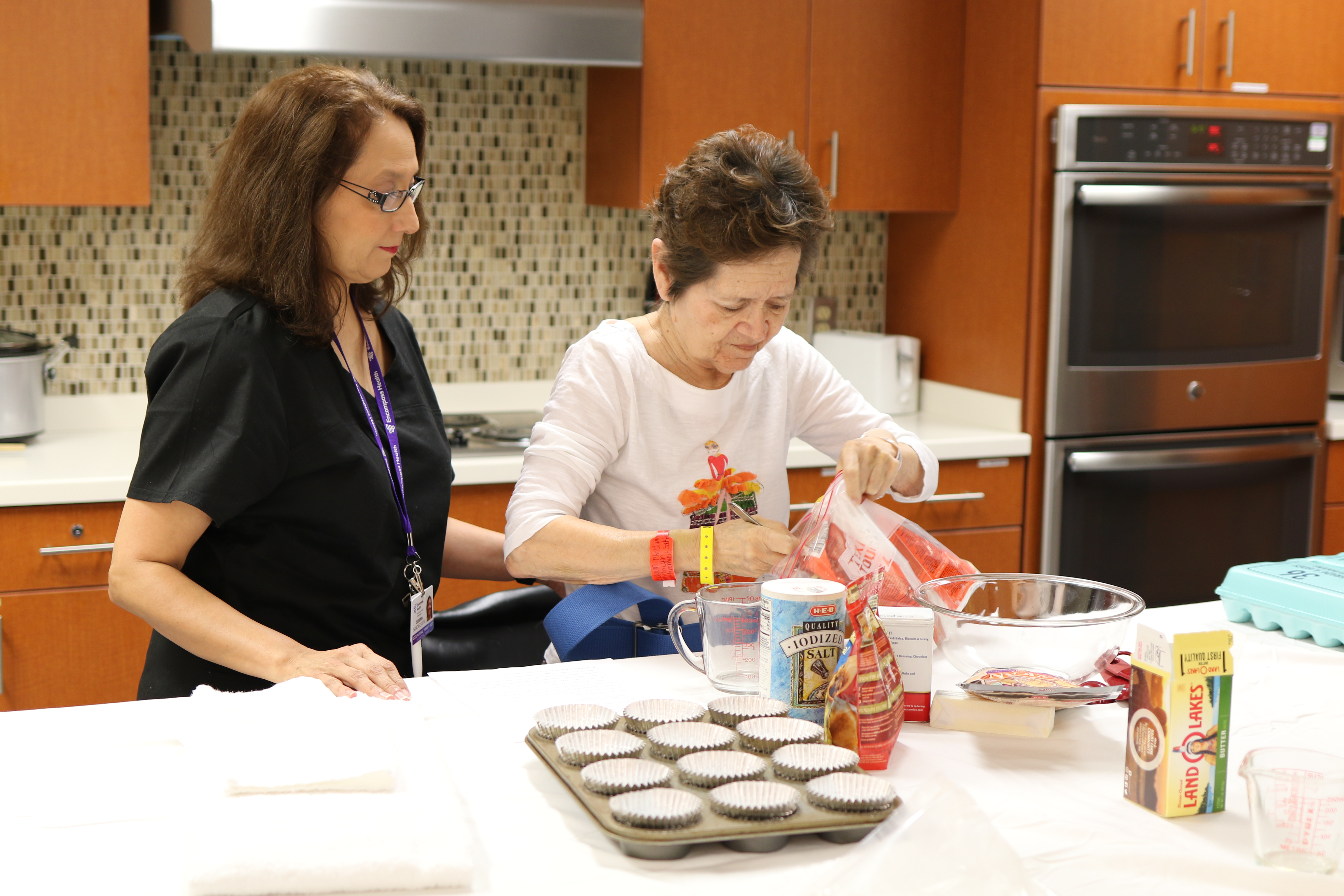 Female therapist works with female patient on making muffins in the activities of daily living kitchen at inpatient rehabilitation hospital