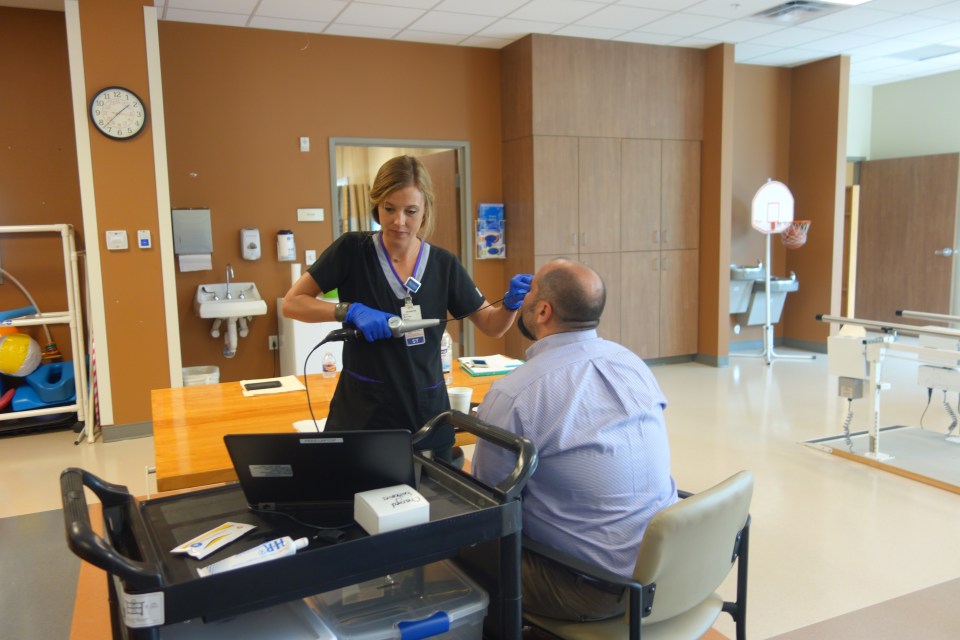 Encompass Health Austin's Megan Moore test the FEES swallowing tool on an employee.