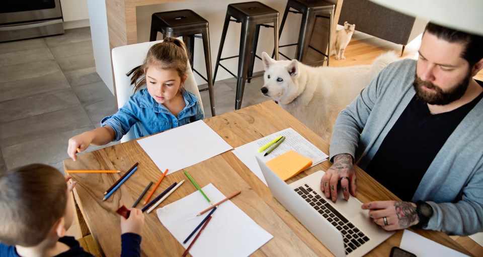 A man works from home with kids and pets
