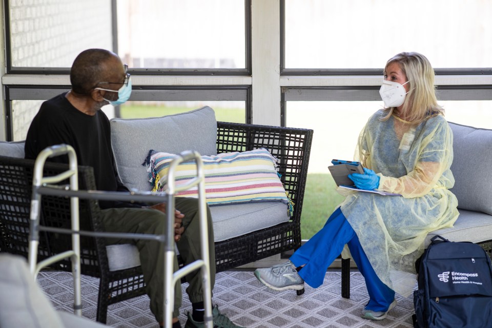 A patient and a home health nurse sit on the patient's porch.