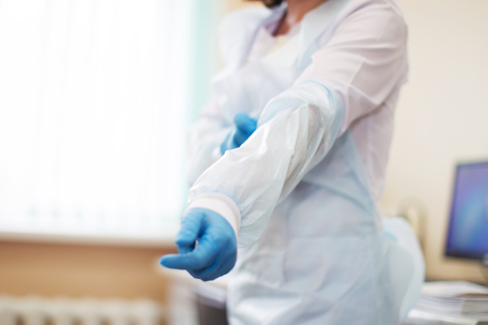 Clinician wearing gown puts on gloves