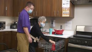 Male therapist working with female patient in a mock kitchen setting. Patient is practicing loading dishes into the dishwasher