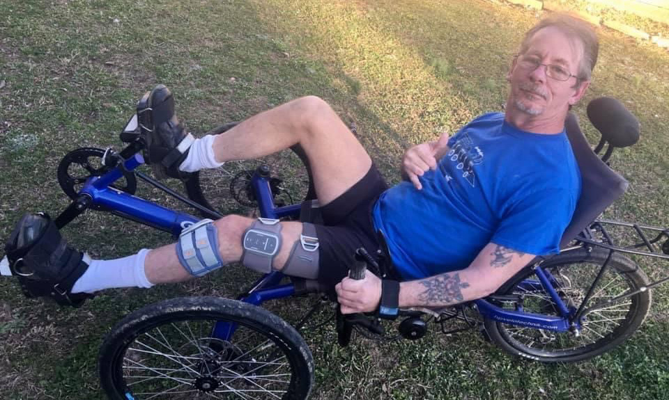 Stroke survivor Dean Tisdale rides his recumbent bicycle.