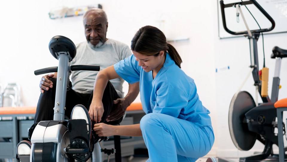 PT helping patient on exercise bike